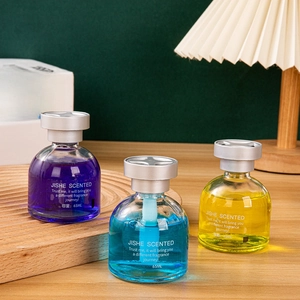 Three 65ml glass car diffusers in purple, blue, and yellow on a wooden desk