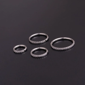 Boucles d'oreilles créoles en acier et zircone en quatre tailles sur fond noir poli