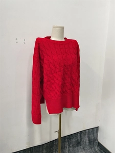 Detail of red knitted sweater showing intricate cable knit patterns and crew neckline