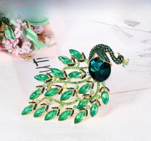 Detailed macro view of vintage peacock brooch with green crystals and gold plating