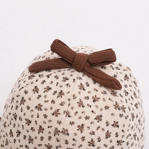 Detailed macro view of vintage floral print baby hat with brown ribbed bow decoration