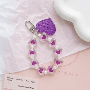 Portachiavi a cuore in pelle viola con perline trasparenti su sfondo rosa