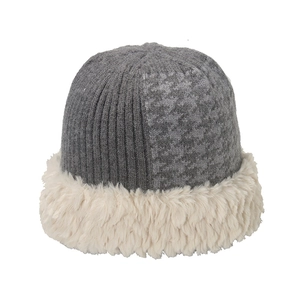 Close-up of winter knit beanie with houndstooth texture and plush faux fur trim detail