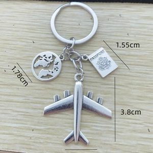 Silver travel keychain featuring mini airplane, globe, and passport charms on wood background
