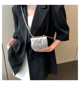 Detail of a silver quilted micro bag with gold chain strap and metallic twist lock