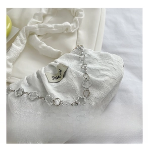 Close-up of white lace shoulder bag featuring decorative silver flower chain and pleated strap