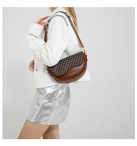 Close-up of brown leather crossbody saddle bag with checkerboard pattern and chain strap
