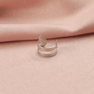 Polished silver double-ring stainless steel ear clip detail on pink fabric background