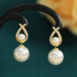 Detail view of gold pearl earrings with a double pearl design and sparkling zircons
