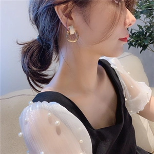 Elegant gold double hoop earrings with white cat eye stone on model, retro geometric style