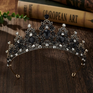 Detailed macro view of a vintage gold crown with black crystals on a dark wood table