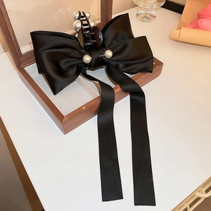 Détail de pince à cheveux noeud en satin noir avec perles dans un coffret en bois