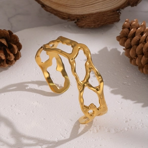 Golden geometric hollow cuff bracelet with irregular minimalist design on a white surface