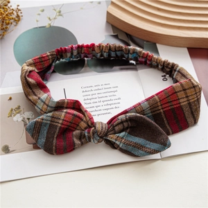 Detailed view of vintage plaid knotted headband with bow on a rustic wooden tray