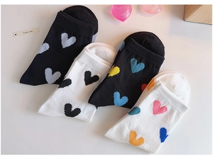 Flat lay of four pairs of cotton crew socks in black and white with colorful heart patterns