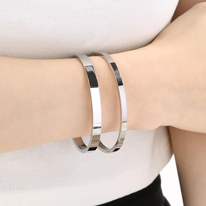Close-up of polished silver minimalist square-line bangles worn on a model's wrist