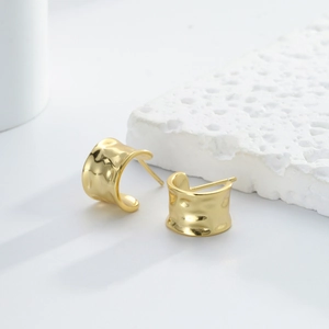 Vintage s925 silver golden C-shaped hoop earrings with textured surface on a white stone