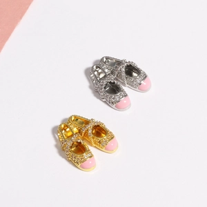 Macro detail of silver and gold ballet slipper pendants with pink enamel and crystals