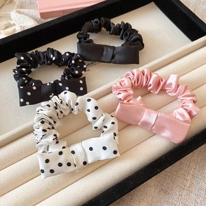 Detail of 4-pack satin bow hair scrunchies in polka dots and solid colors on a velvet tray