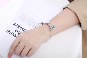 Detail van zilveren roestvrijstalen armband met gegraveerde hart- en ronde bedels