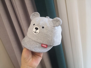Close-up of grey striped baby cap with cute bear ears and detailed facial embroidery