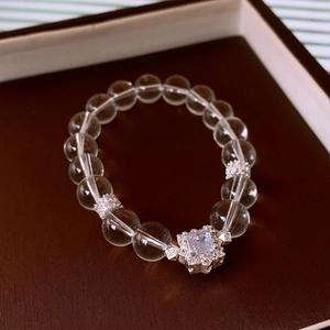 Detail of beaded flower crystal bracelet with zircon square pendant on wood background