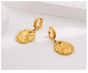 Detailed macro view of gold-plated circular earrings featuring unique hammered texture finish