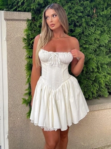 Mini robe corset blanche avec ourlet en dentelle et laçage lors d'une séance en plein air