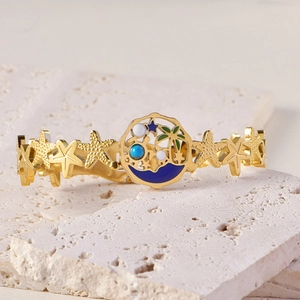 Gros plan du bracelet doré thème océan avec charms étoile de mer et palmier