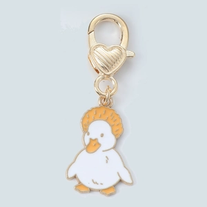 Detail of cartoon duck keychain with orange afro hair and golden heart clasp