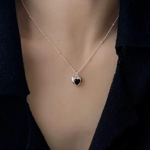Close-up of S925 silver necklace with black onyx heart pendant worn on model