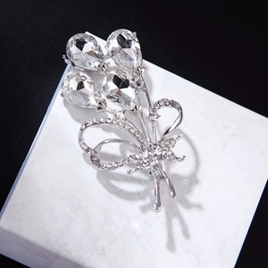 Elegant silver flower brooch with clear water drop crystals on white marble surface