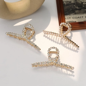 Close-up of golden hair claws with pearls and rhinestones on a minimalist background