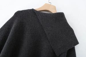 Detail view of dark grey knitted poncho cape with asymmetric neckline and fine texture