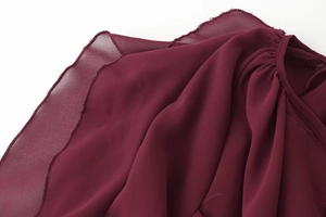Detailed close-up of wine red chiffon fabric with pleats and neat edge stitching