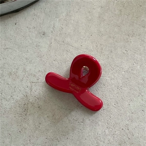 Detail view of a glossy red acetate hair claw clip with handmade gold lettering