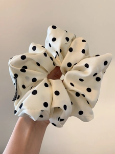 Close-up of fluffy white scrunchie with black polka dots in high-quality crepe fabric