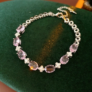 Detailed macro view of pink zircon flower bracelet on dark green velvet background