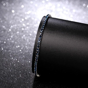 Macro shot of a 2mm silver stretch bracelet with blue crystals on a black display stand