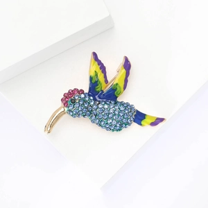 Macro shot of colorful enamel hummingbird brooch with vibrant blue rhinestones and gold plating
