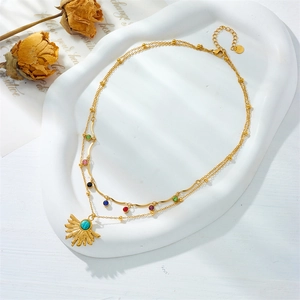 Detail of layered gold necklace featuring colorful gemstones and turquoise sun pendant