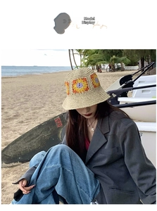 Detail of hand-crocheted beige bucket hat with flower pattern shown on a sunny beach