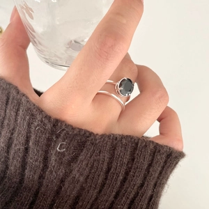 Close-up of double-layer S925 silver ring with oval black zircon on a hand holding a glass