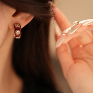 Detailed shot of a gold-plated C-shaped earring with red enamel and square zirconias