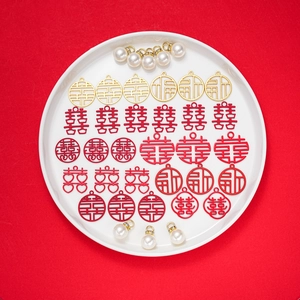 Close-up of red and gold Chinese wedding charms with faux pearls on a white plate