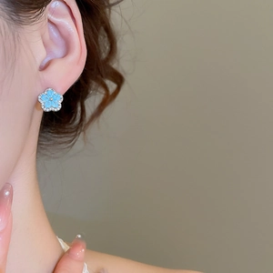 Detailed close-up of light blue flower stud earring with sparkling zircon borders
