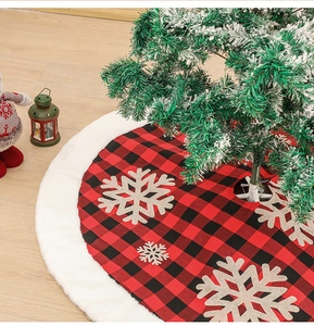 Detail of red and black plaid Christmas tree skirt with white plush trim and snowflake patches
