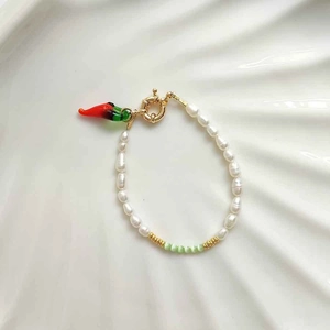 Detailed shot of handmade pearl necklace with green beads and a chili pepper charm