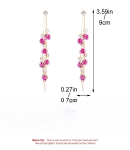 Detail of elegant gold flower earrings with pink roses and long crystal tassels
