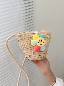 Detailed close-up of straw woven bag featuring colorful polka dots and a smiley flower charm